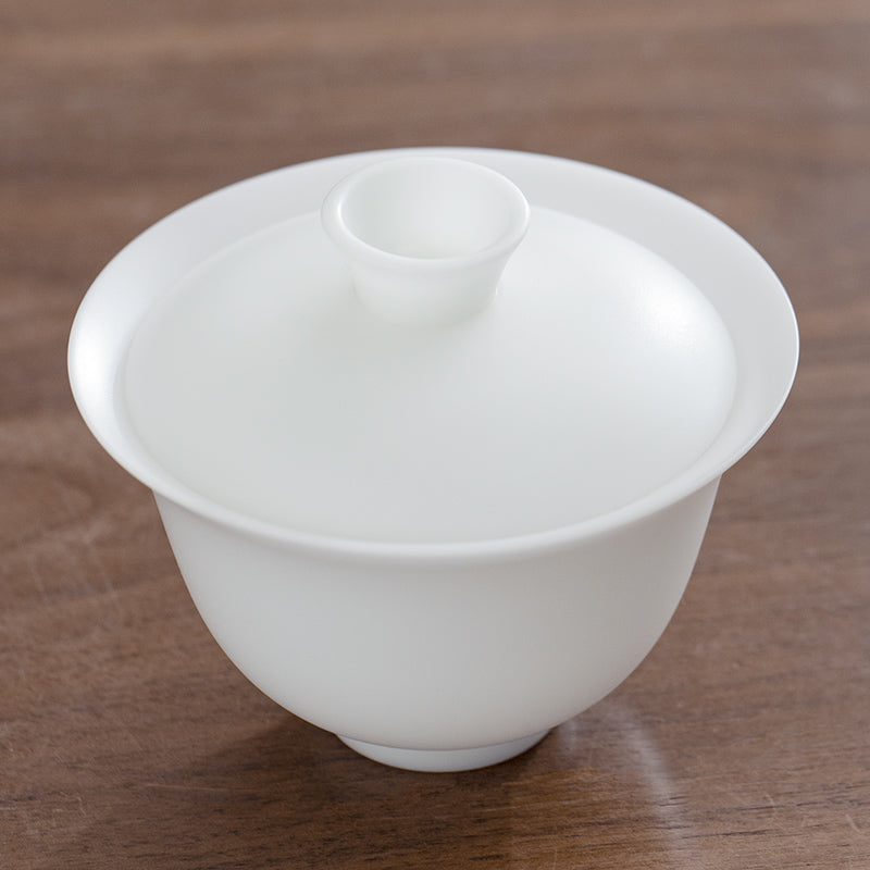 White ice jade ceramic teacup with lid on a wooden surface
