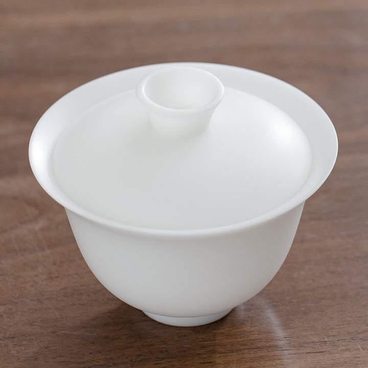 White ice jade ceramic teacup with lid on a wooden surface
