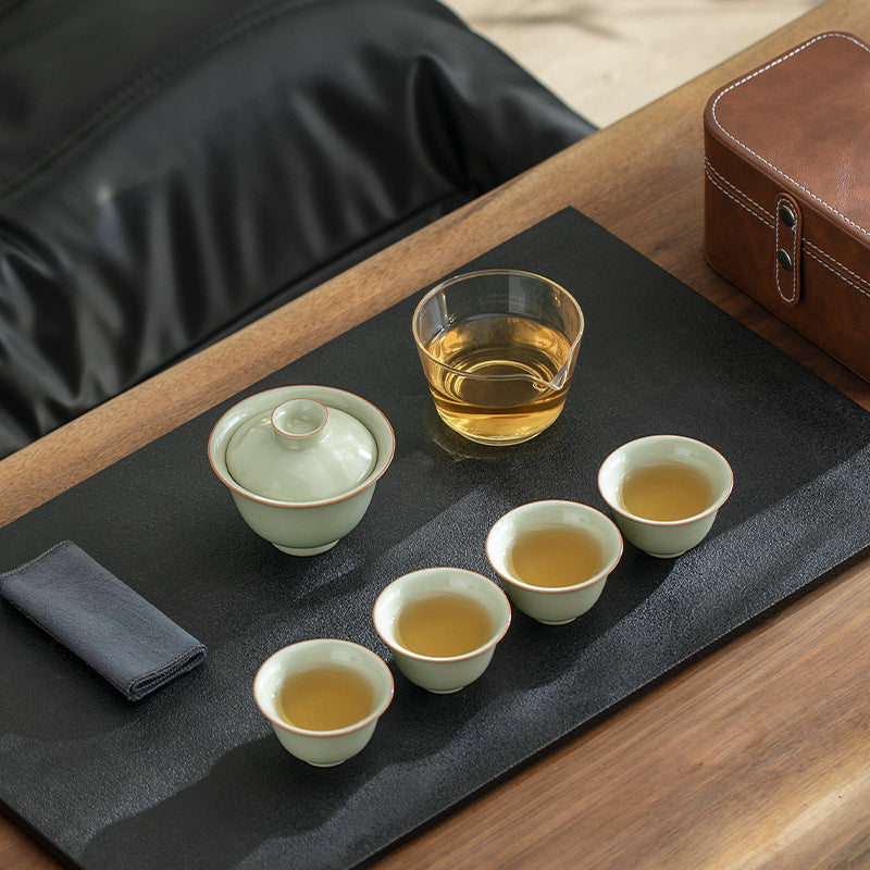 Tea set with cups and a teapot on a black tray with a wooden surface.