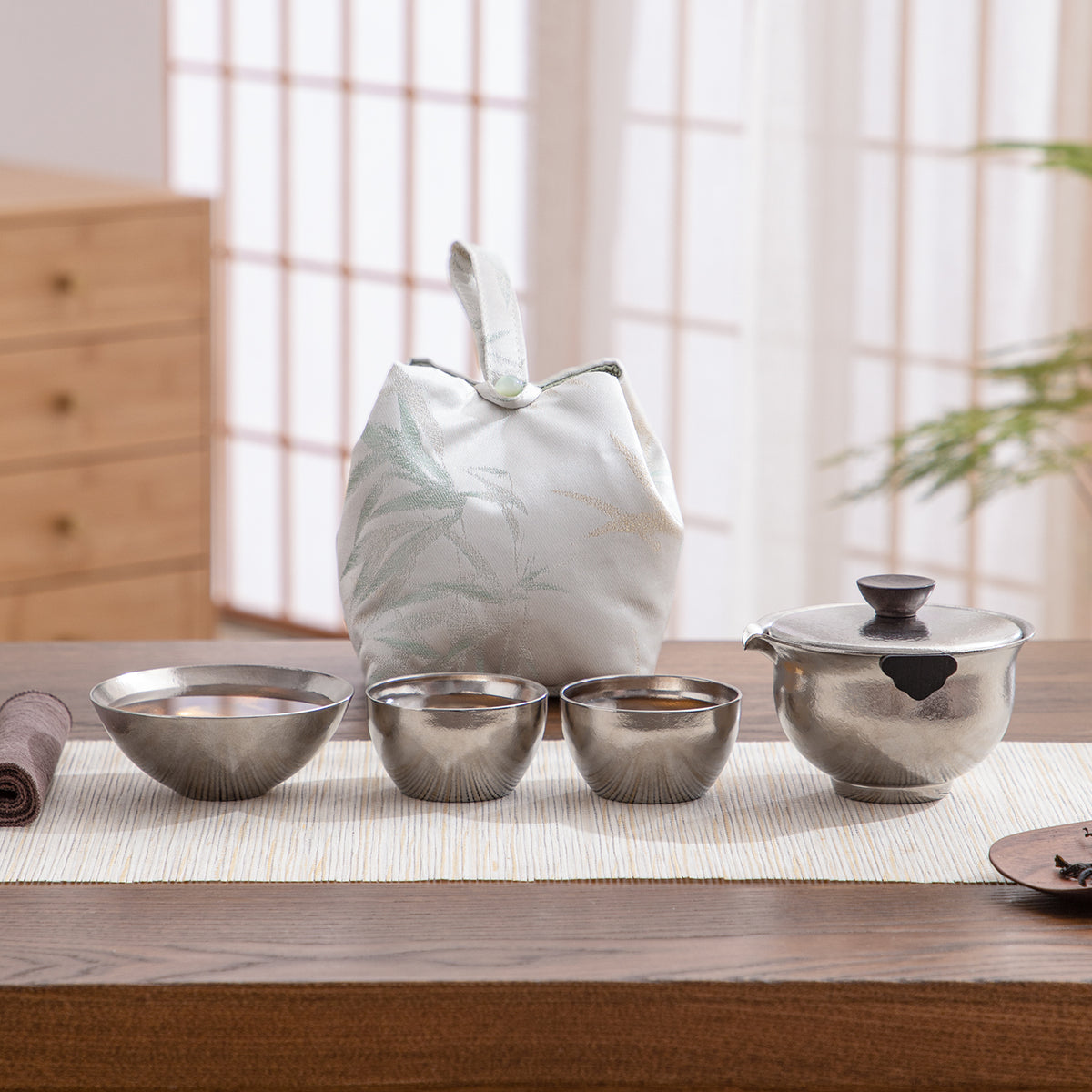 Set of metallic bowls and a white bag on a wooden table with a blurred background