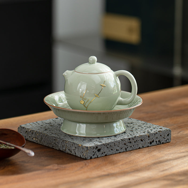Ceramic teapot with lid on a matching saucer on a wooden surface