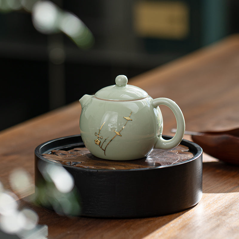 Green ceramic teapot with floral design on a wooden table