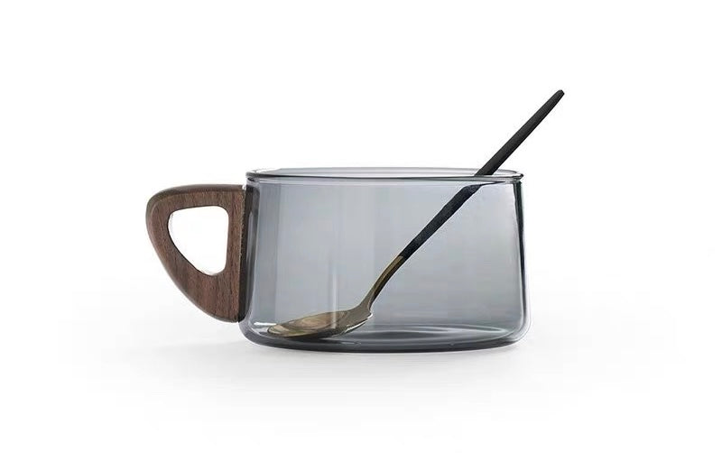 Clear glass mug with wooden handle and black spoon on a white background