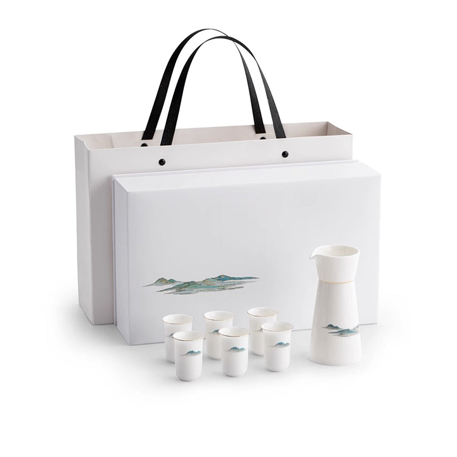 White ceramic sake set with six cups and a pitcher, accompanied by a matching gift bag on a white background.