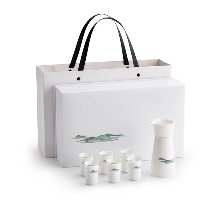 White ceramic sake set with six cups and a pitcher, accompanied by a matching gift bag on a white background.