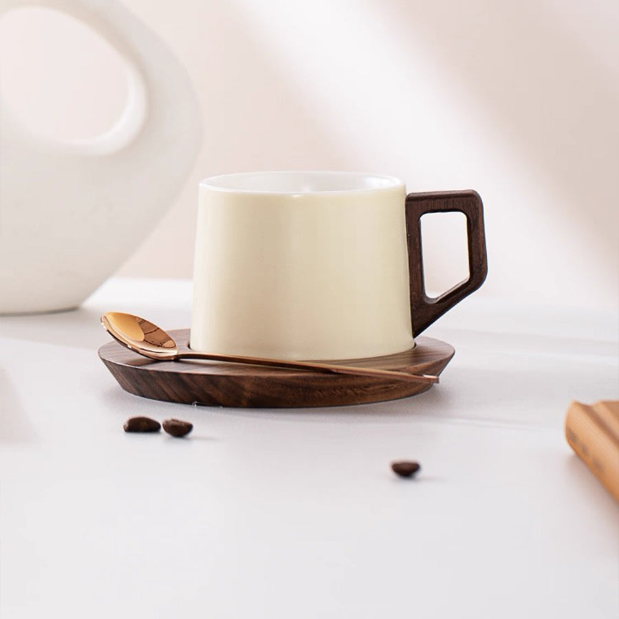 Cream mug with wooden handle on a wooden coaster with coffee beans on a light background