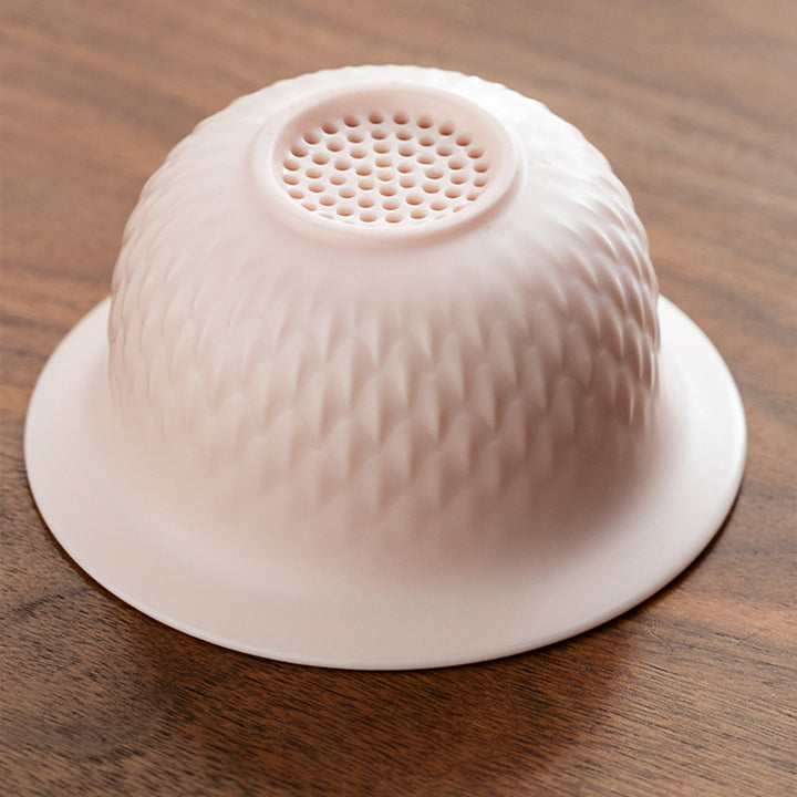 Pink silicone strainer on a wooden surface