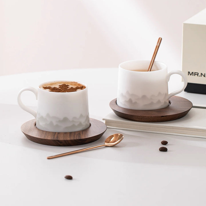 Two white ceramic mugs with wooden coasters on a light surface, accompanied by coffee beans and a spoon. can be personalized with name/logo