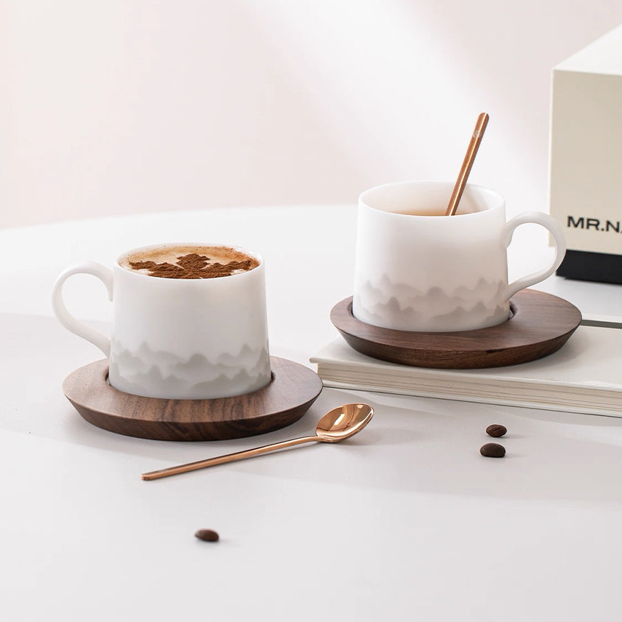 Two white ceramic mugs with wooden coasters on a light surface, accompanied by coffee beans and a spoon. can be personalized with name/logo