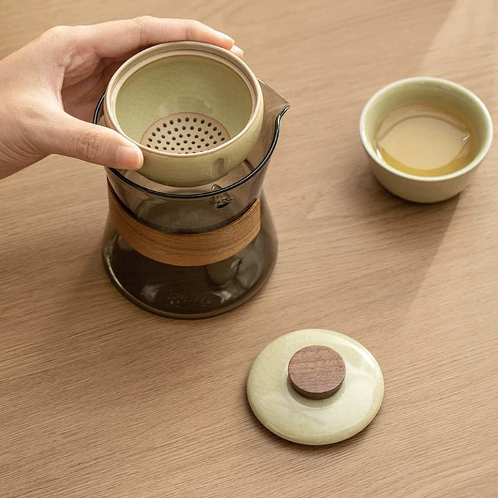 Tea-making set with a teapot, cup, and lid on a wooden surface