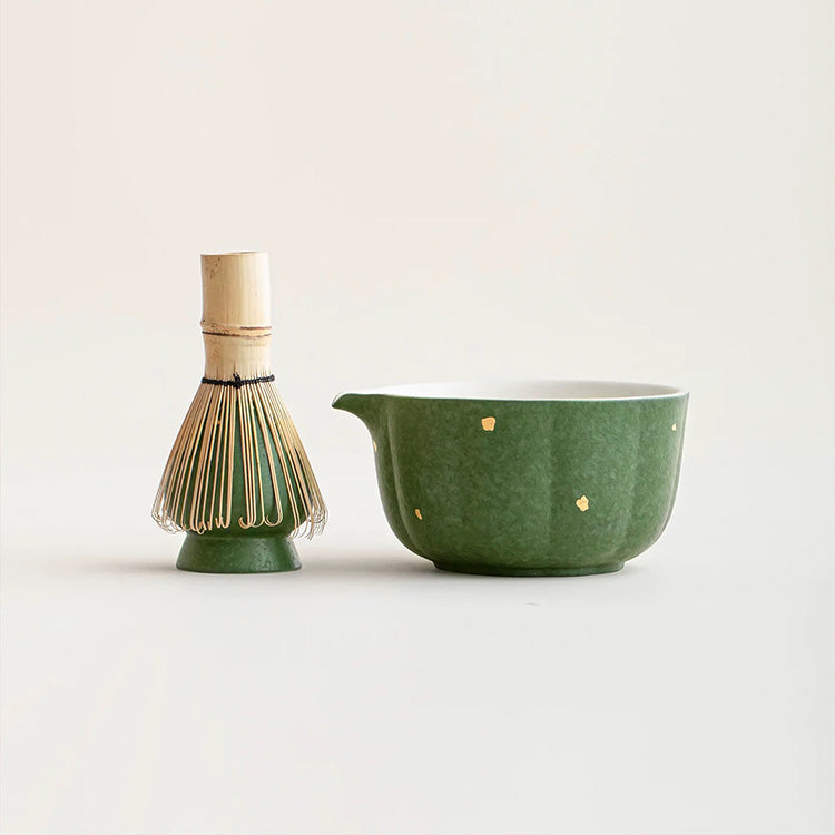 Green ceramic matcha bowl set with bamboo whisk on a light background