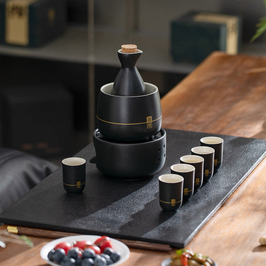 Black ceramic sake set with warmer and 6 cups on a wooden table