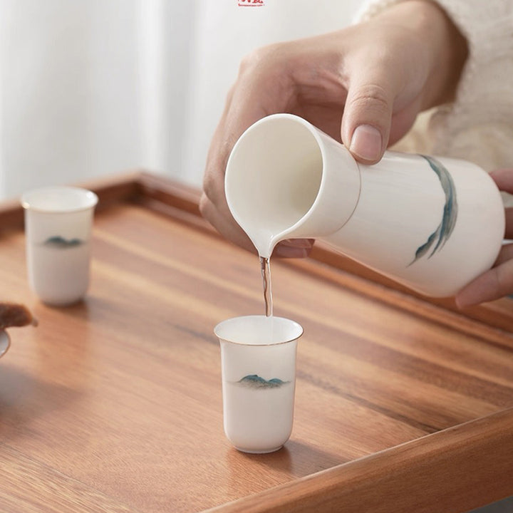 Person pouring saki from a white ceramic cup onto another on a wooden tray.