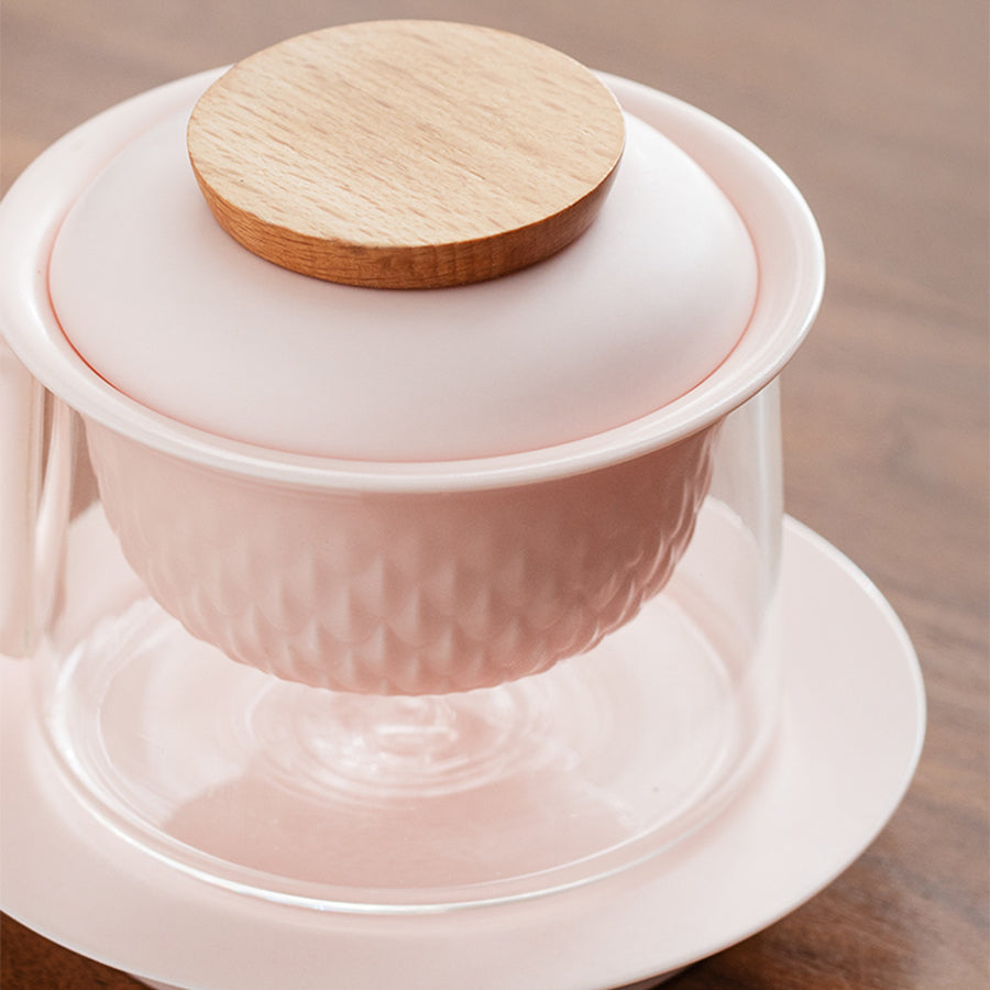 pink ceramic teapot with wooden lid on a wooden surface