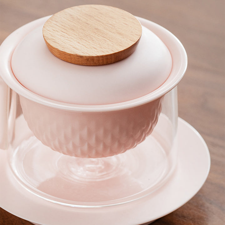 pink ceramic teapot with wooden lid on a wooden surface