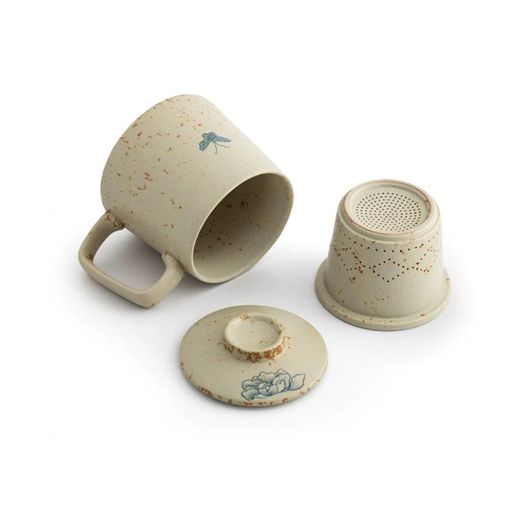 Set of ceramic tea accessories including a cup, filter, and lid on a white background