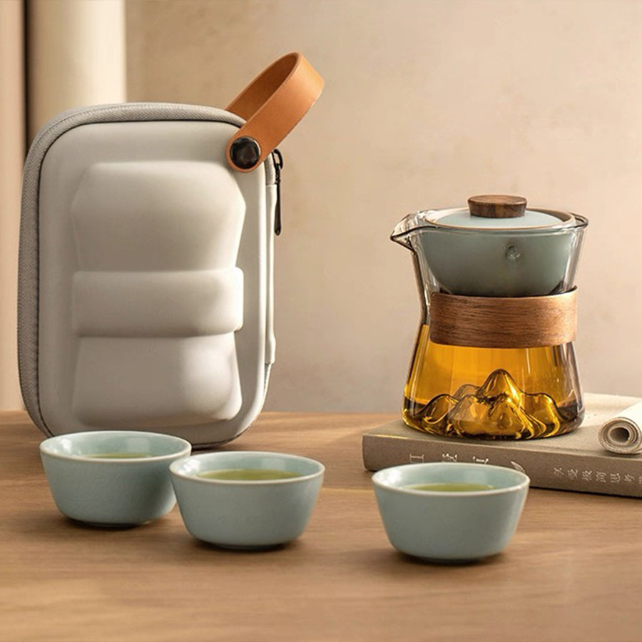 Tea set with teapot, cups, and carrying case on a wooden surface.