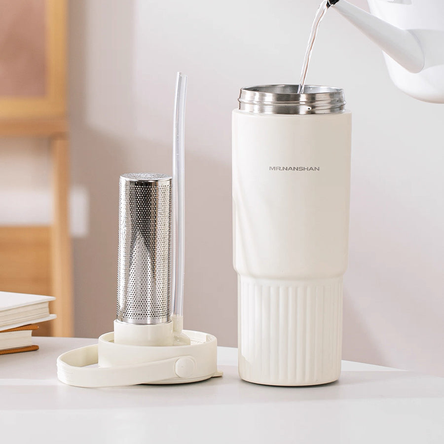 White thermos with tea infuser on a table, with a blurred background