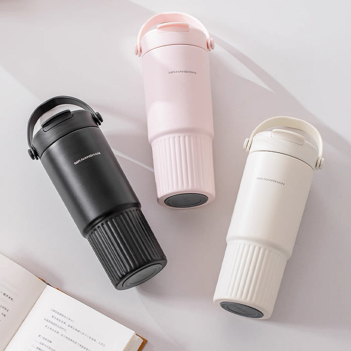 Three thermos bottles in black, pink, and white on a light surface.